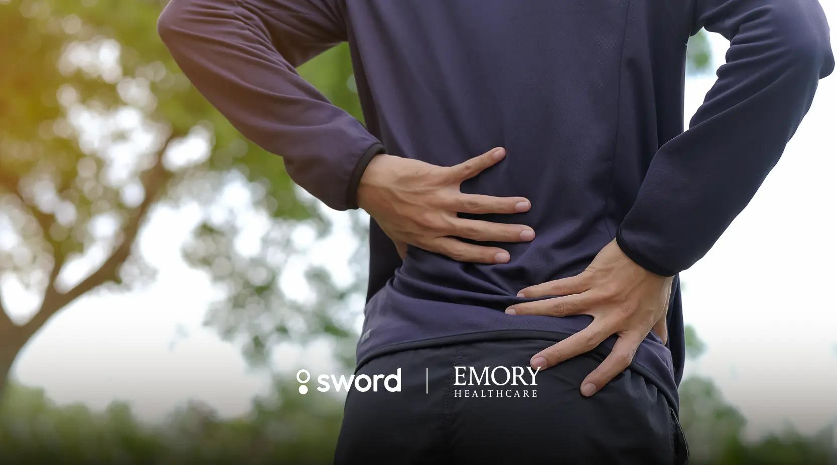 Person outdoors holding their lower back in discomfort, with logos for Sword and Emory Healthcare visible.