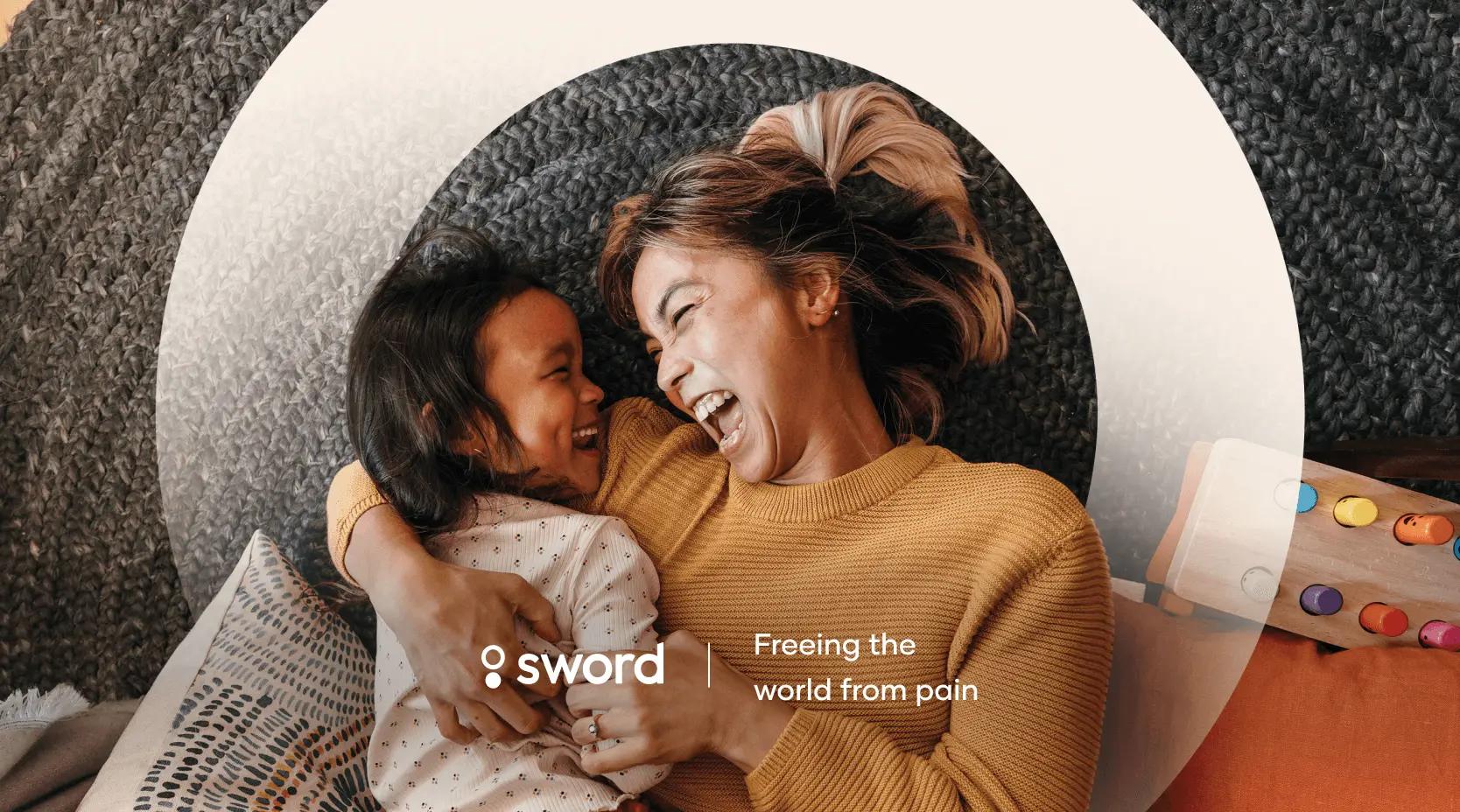 A woman and child laughing together on a couch, surrounded by cozy textures. Text reads: "Sword - Freeing the world from pain."