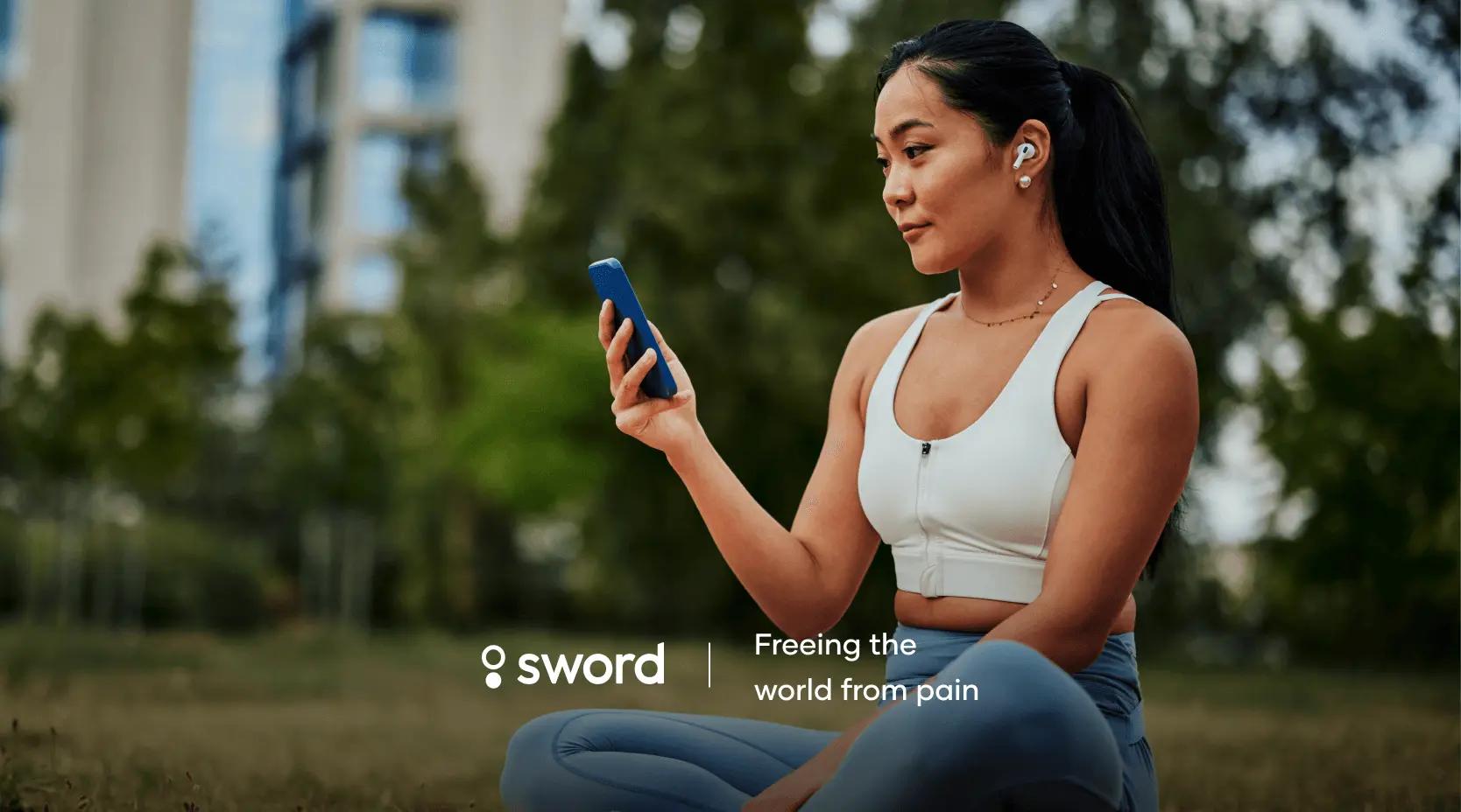 A woman in athletic wear sits outdoors, looking at her phone. Text reads "sword: Freeing the world from pain."